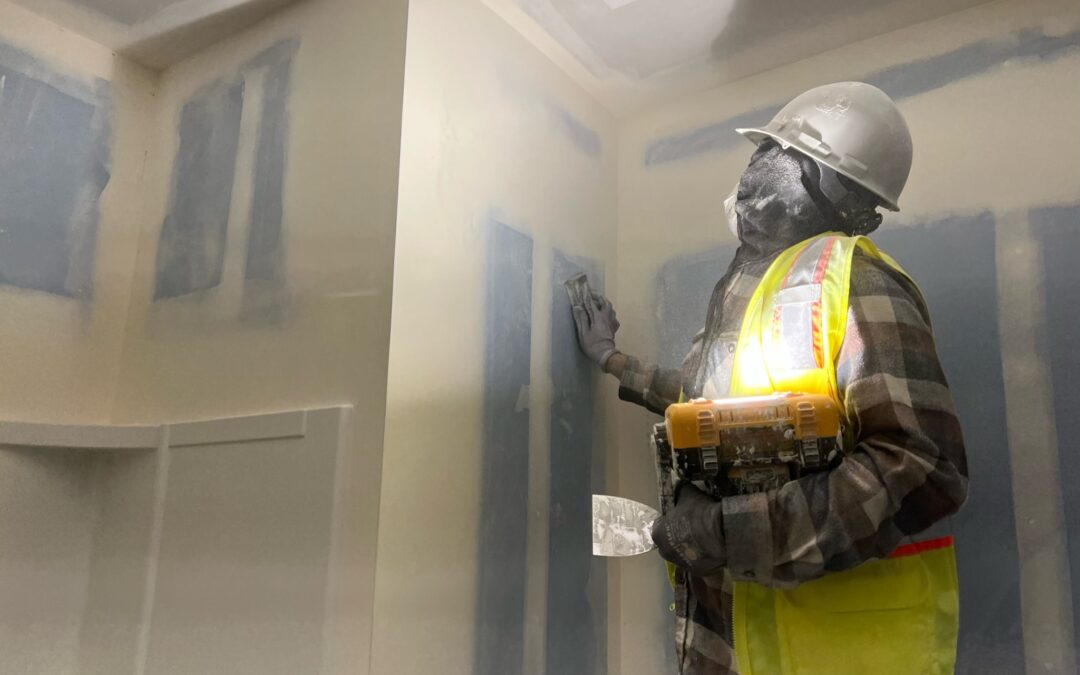 A member of the Magnum Drywall team is in the process of installing drywall.